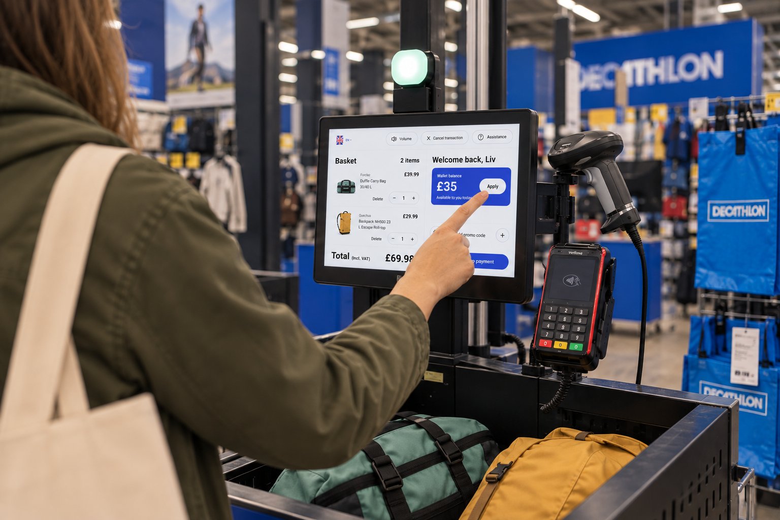 A customer at a Decathlon self-checkout taps Apply to use their £35 Wallet balance on a duffle bag and backpack.